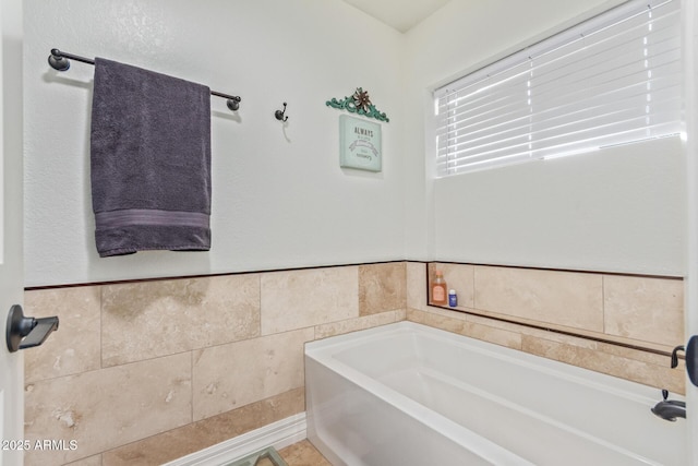 full bathroom featuring a bath and tile walls
