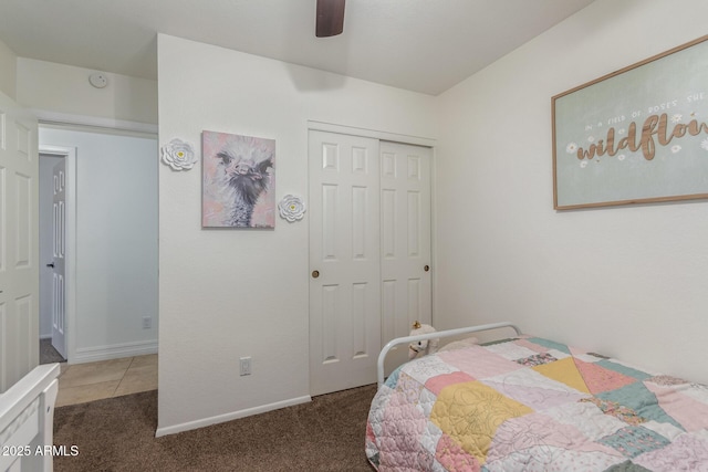 tiled bedroom featuring a closet, carpet floors, baseboards, and a ceiling fan