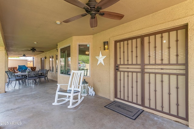entrance to property with stucco siding, ceiling fan, and outdoor dining space