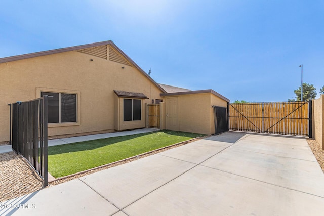 back of house with a gate, stucco siding, fence, and a patio area