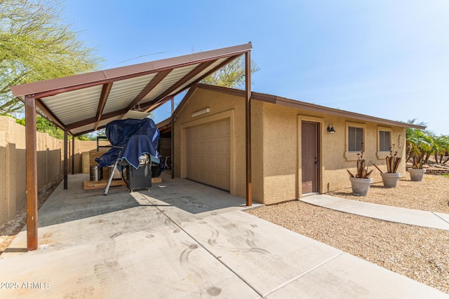 exterior space with driveway, stucco siding, fence, a carport, and a garage