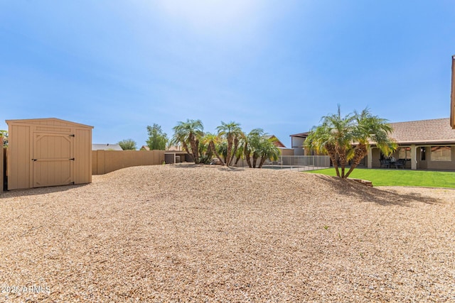 view of yard with an outdoor structure, a fenced backyard, and a shed