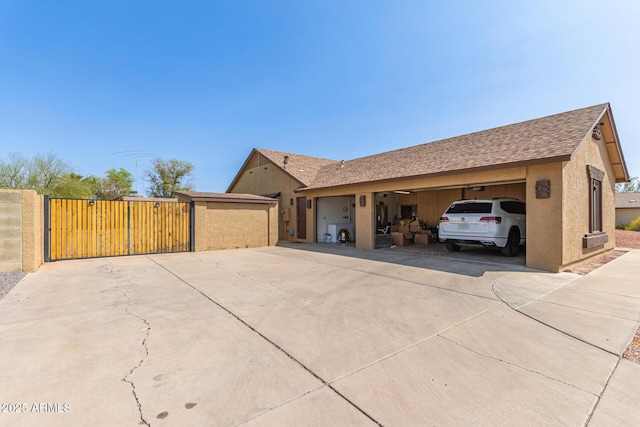 view of side of home featuring stucco siding, an attached garage, concrete driveway, and a gate