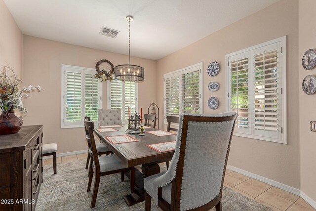 dining area with light tile patterned floors, an inviting chandelier, visible vents, and baseboards