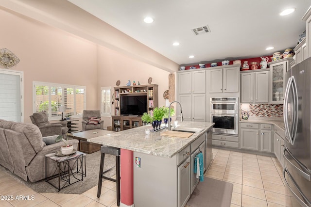 kitchen featuring visible vents, light tile patterned floors, a sink, appliances with stainless steel finishes, and open floor plan