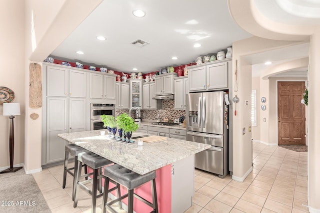 kitchen featuring light tile patterned flooring, under cabinet range hood, visible vents, and stainless steel appliances
