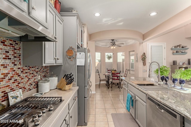 kitchen with under cabinet range hood, stainless steel appliances, light tile patterned floors, a sink, and ceiling fan