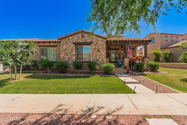 view of front of house with stucco siding, a tile roof, a front lawn, and ceiling fan