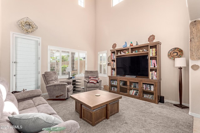 living area featuring a high ceiling and baseboards