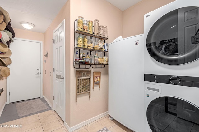 washroom with baseboards, stacked washing maching and dryer, laundry area, and light tile patterned floors
