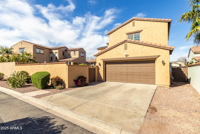 mediterranean / spanish home featuring a tile roof, concrete driveway, fence private yard, and stucco siding