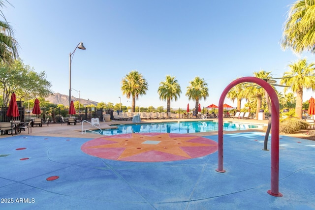 view of home's community with a pool, a patio area, and fence