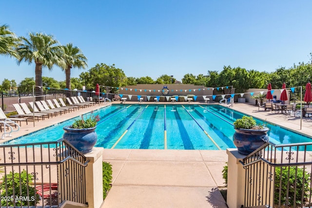 community pool with fence and a patio