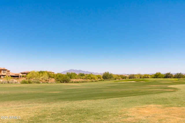view of home's community with a yard, golf course view, and a mountain view
