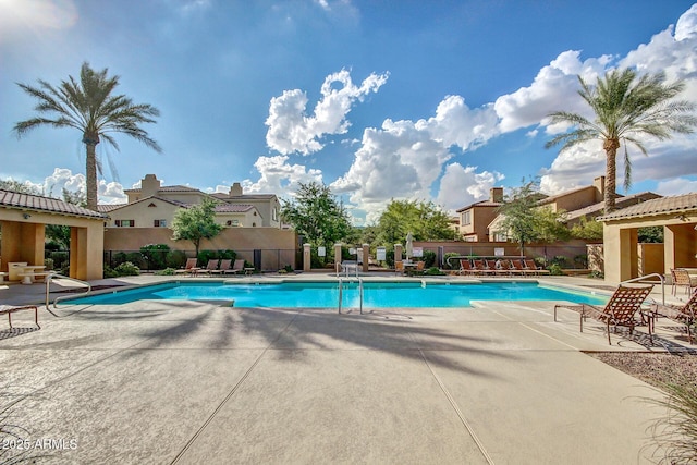 community pool featuring a residential view, a patio area, and fence