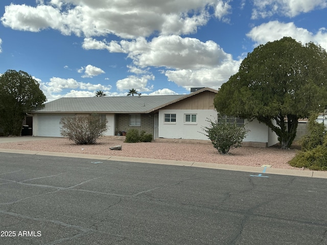 ranch-style home with metal roof, driveway, and an attached garage