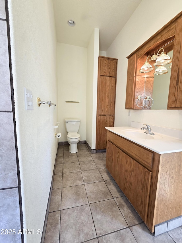 bathroom with toilet, vanity, and tile patterned flooring