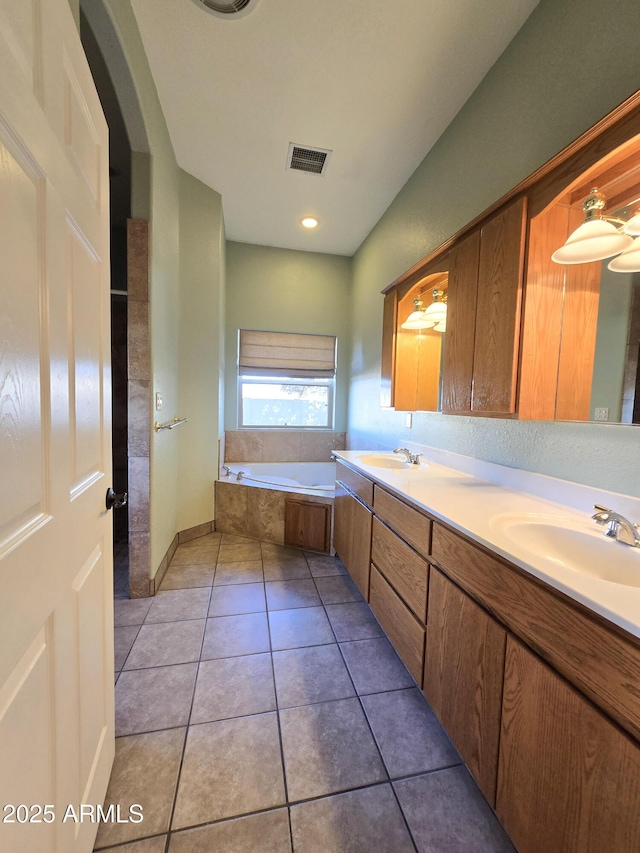 bathroom featuring tile patterned flooring, tiled tub, and vanity