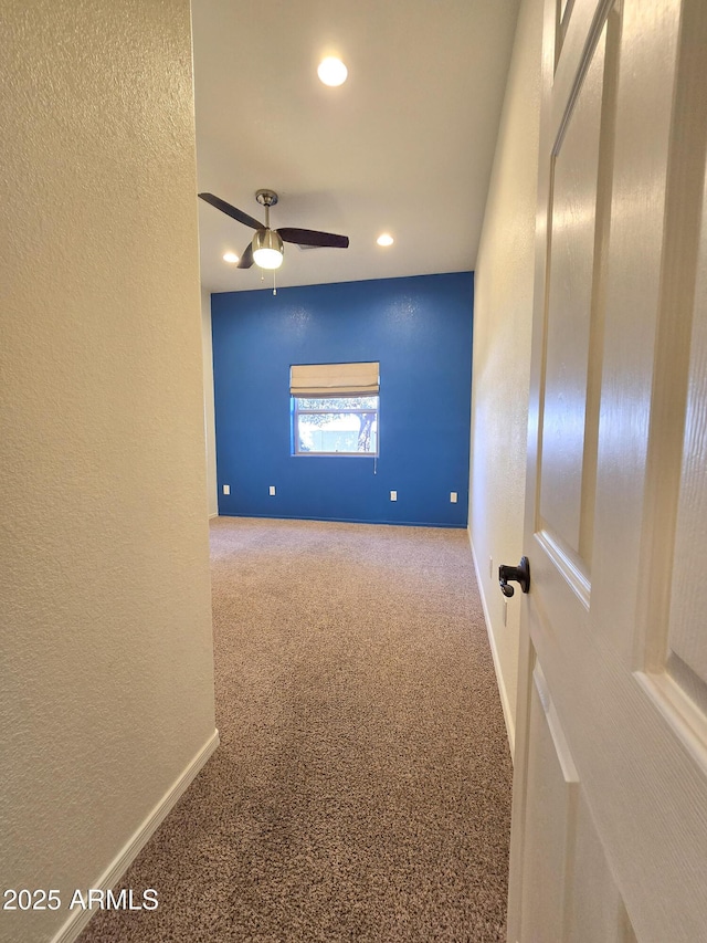 unfurnished room with ceiling fan and carpet