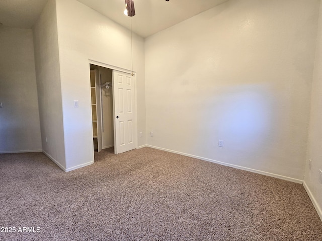 unfurnished bedroom with a high ceiling, ceiling fan, a closet, and carpet floors