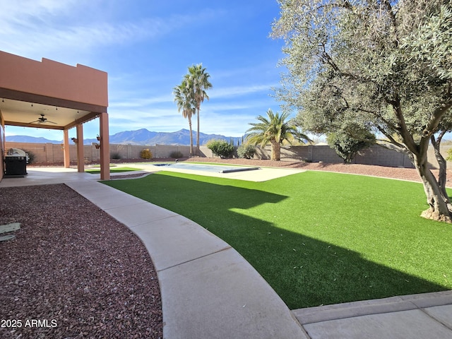 view of yard with a mountain view, a patio area, and ceiling fan