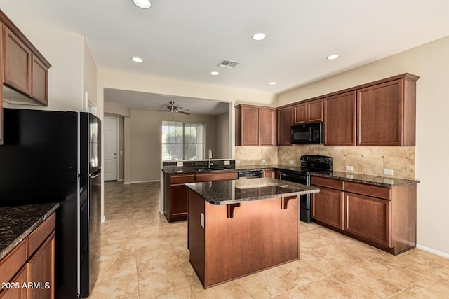 kitchen with visible vents, a breakfast bar, dark stone countertops, black appliances, and a sink