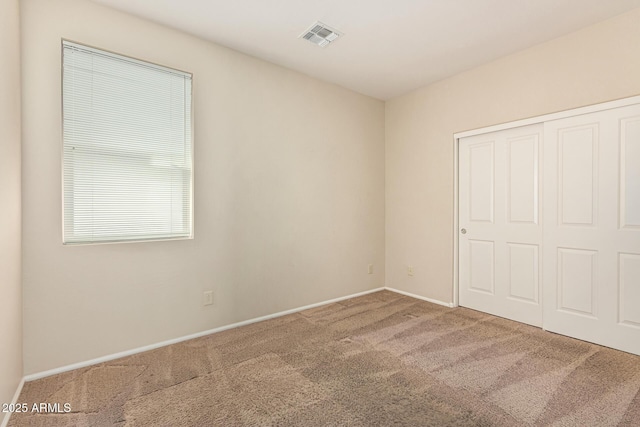 unfurnished bedroom with baseboards, carpet, visible vents, and a closet