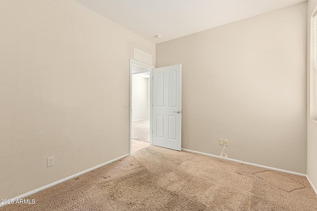 empty room featuring carpet floors, visible vents, and baseboards