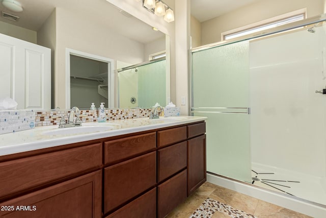 full bathroom featuring tasteful backsplash, a sink, a walk in closet, and a shower stall