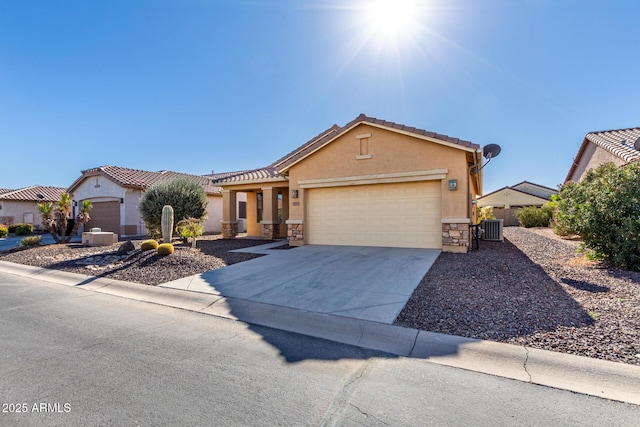 view of front of house with a garage, concrete driveway, stone siding, central AC, and stucco siding