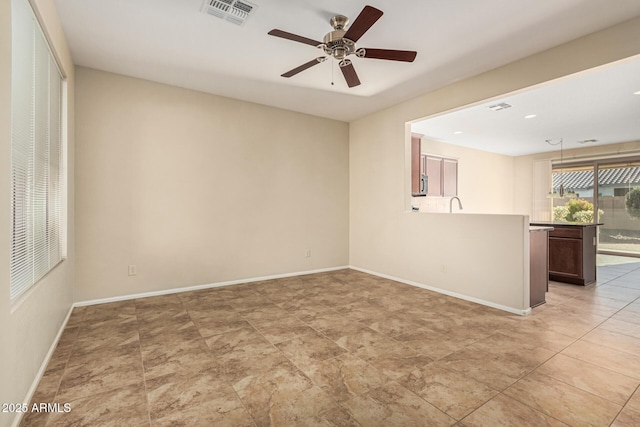 unfurnished room with a ceiling fan, visible vents, and baseboards