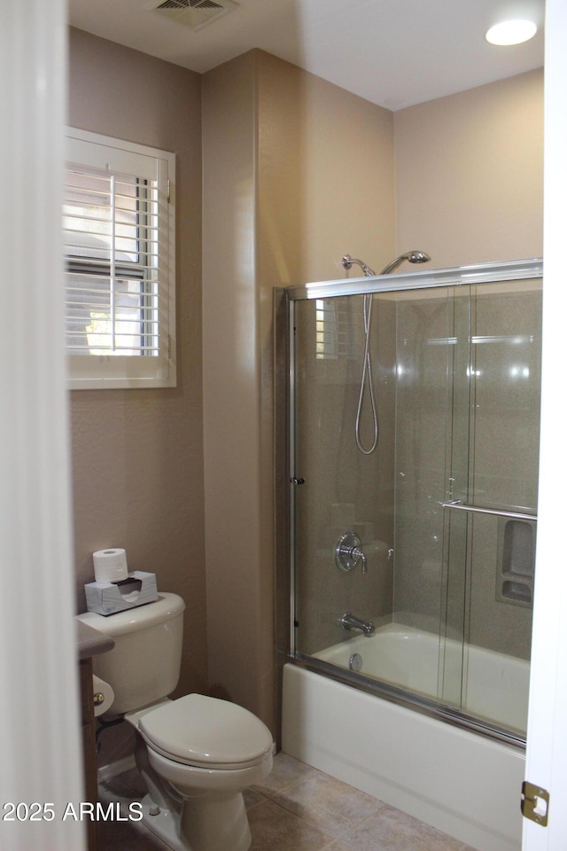 bathroom featuring tile patterned flooring, toilet, and combined bath / shower with glass door