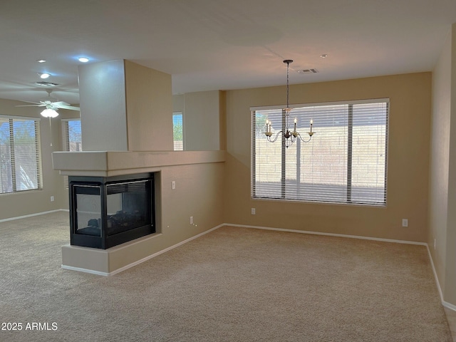 unfurnished living room featuring carpet flooring, a chandelier, and a multi sided fireplace