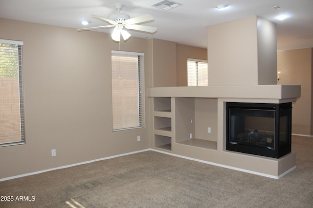 unfurnished living room featuring carpet flooring, ceiling fan, and a multi sided fireplace