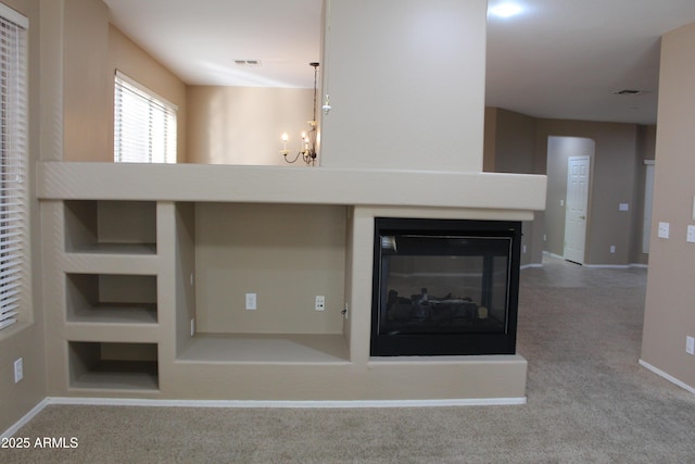 details featuring a notable chandelier, a multi sided fireplace, carpet, and built in features