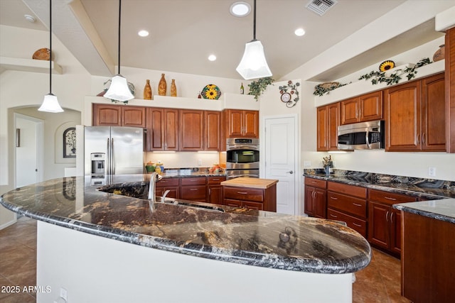 kitchen featuring visible vents, a spacious island, stainless steel appliances, decorative light fixtures, and dark tile patterned floors