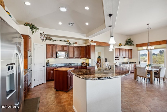 kitchen featuring visible vents, an island with sink, lofted ceiling, an inviting chandelier, and stainless steel appliances