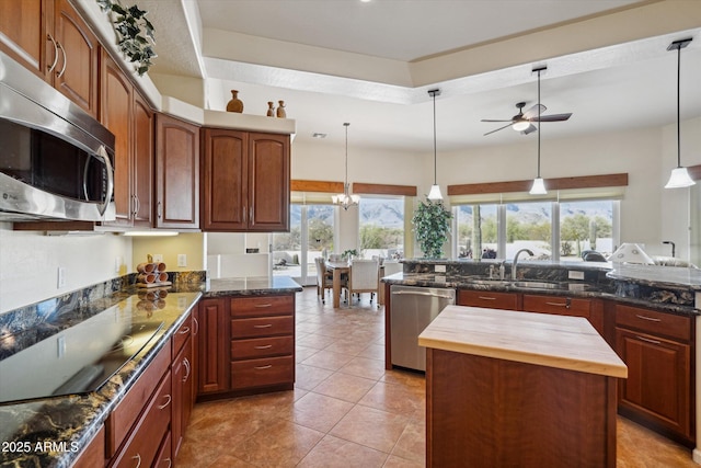 kitchen with a ceiling fan, butcher block counters, appliances with stainless steel finishes, a wealth of natural light, and a center island