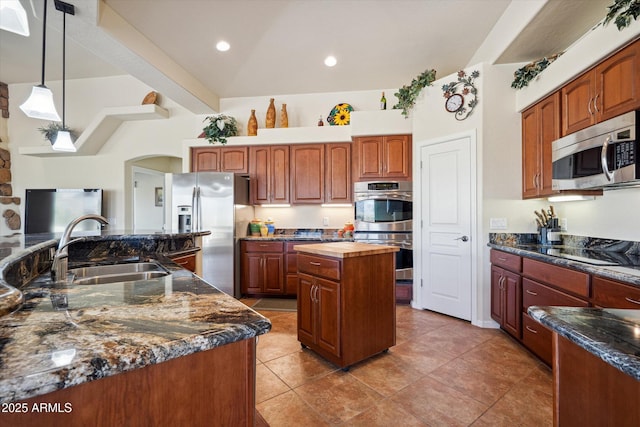 kitchen with lofted ceiling with beams, a kitchen island with sink, a sink, stainless steel appliances, and pendant lighting