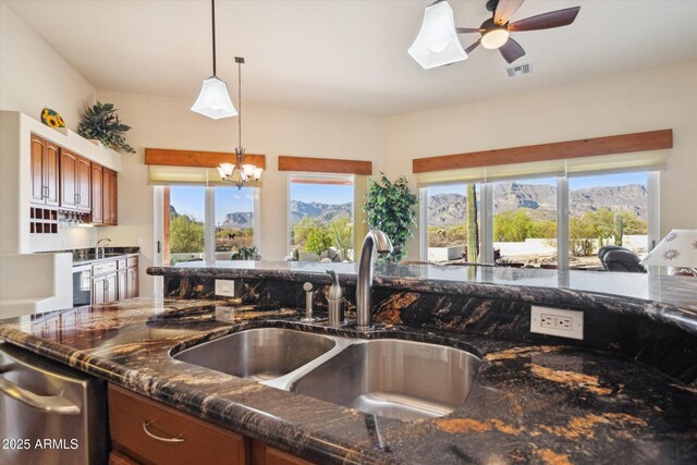 kitchen featuring dark stone countertops, pendant lighting, visible vents, and a sink