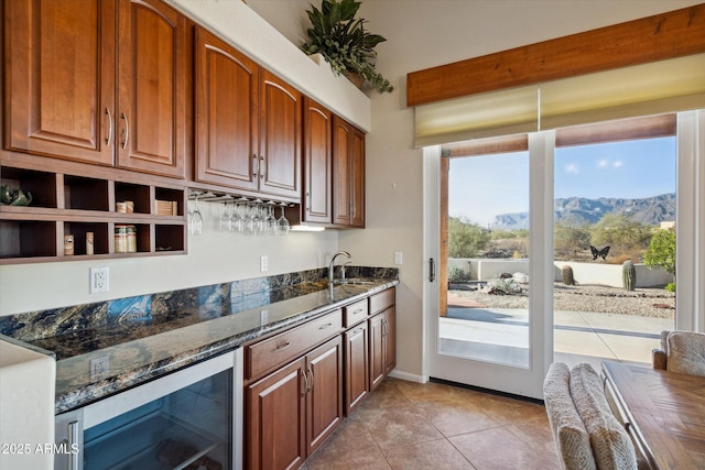 kitchen featuring dark stone countertops, light tile patterned floors, beverage cooler, a sink, and a mountain view