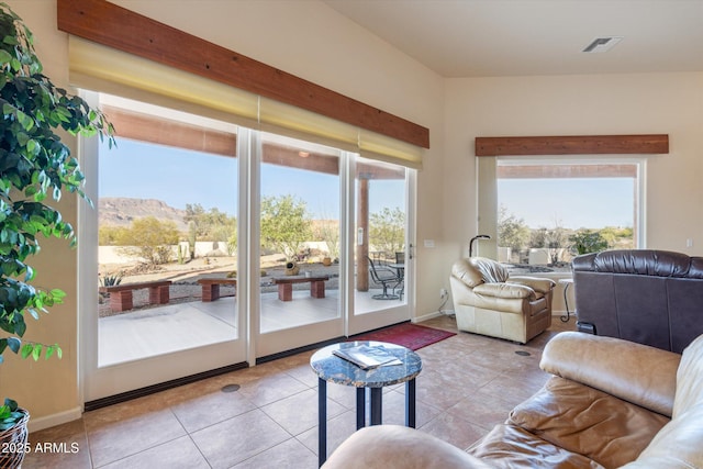 tiled living area with visible vents, plenty of natural light, and baseboards