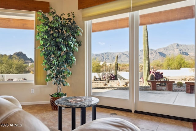 entryway with tile patterned floors, a healthy amount of sunlight, a mountain view, and baseboards