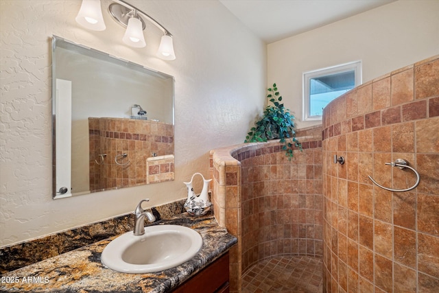 bathroom featuring tiled shower and vanity