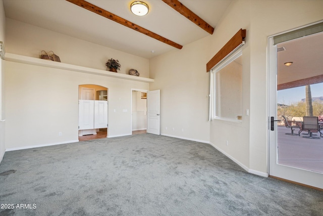 interior space featuring beam ceiling, arched walkways, and baseboards