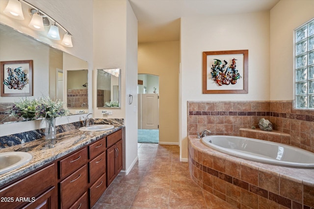 bathroom featuring tile patterned floors, a garden tub, a sink, double vanity, and baseboards