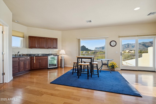 dining space with visible vents, a mountain view, wine cooler, light wood finished floors, and baseboards