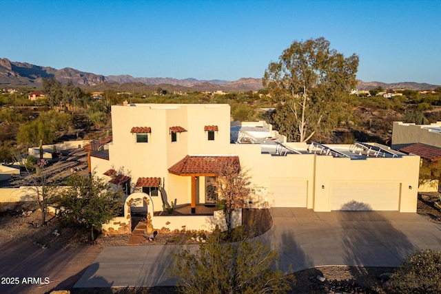 adobe home with a mountain view, concrete driveway, and stucco siding