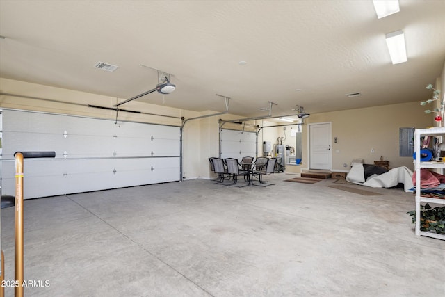 garage with electric panel, a garage door opener, and visible vents