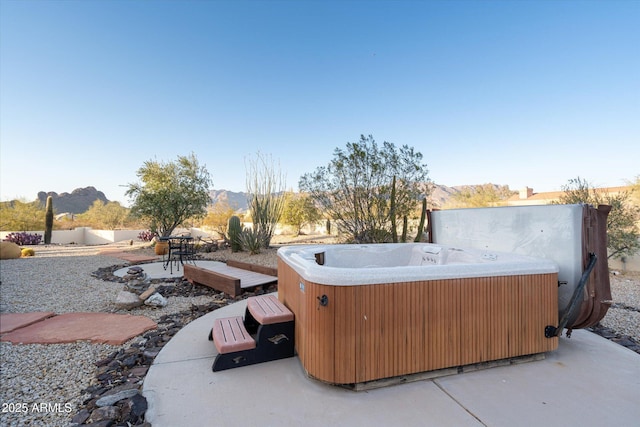 view of patio featuring a mountain view, a hot tub, and fence